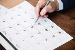 Hand with pen pointing on calendar page